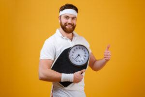 fitness man holding weight scales showing thumbs up